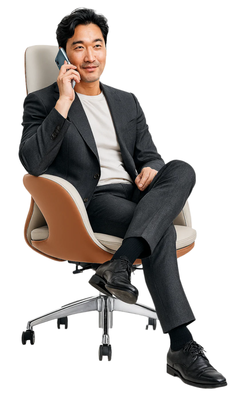 Man in a suit sitting on an office chair while talking on a phone.