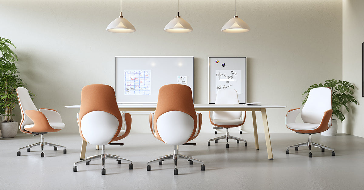 Modern office setup with orange and white chairs around a table, featuring a whiteboard on the wall.