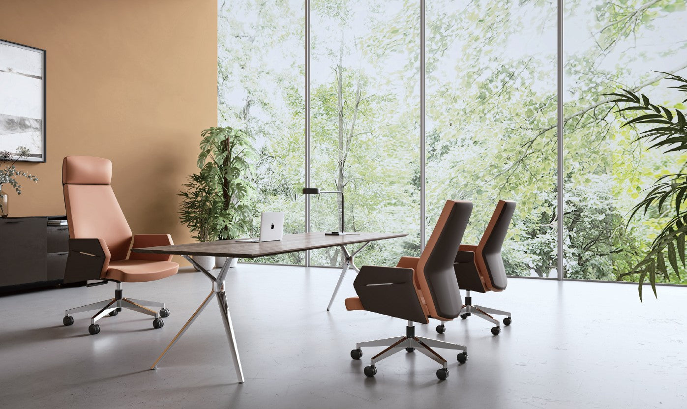 Modern office setup with a large desk and chairs in front of large windows with greenery outside.